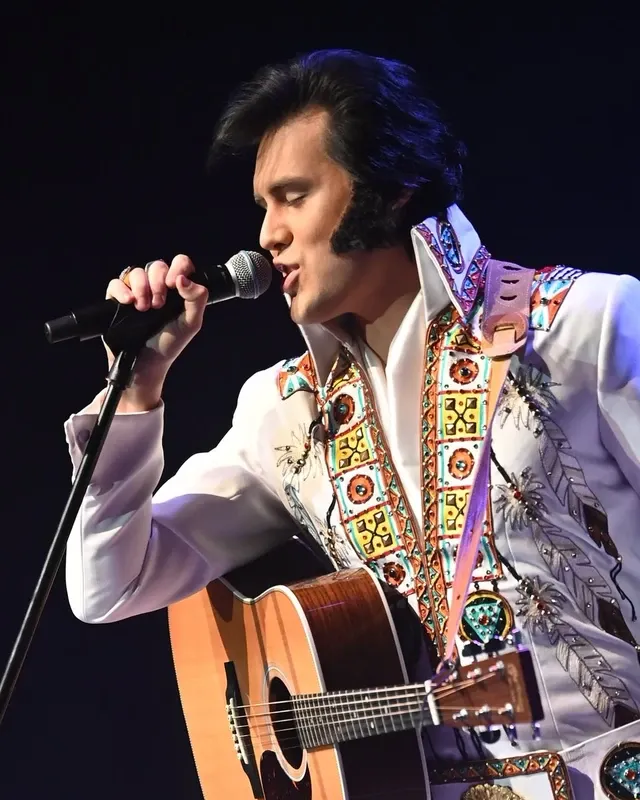Taylor Rodriguez performing in a white stage jumpsuit